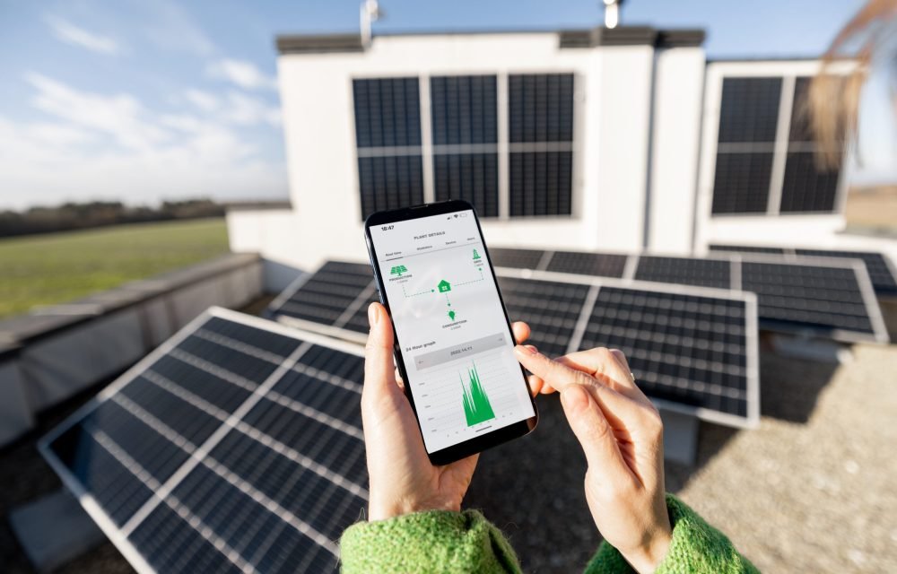 Woman monitors energy production from the solar power plant with mobile phone. Close-up view on phone screen with running program. Concept of remote control of solar energy production